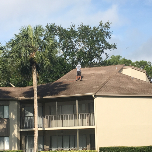 One of men is up on the roof of this Naples home, power washing like a pro.
